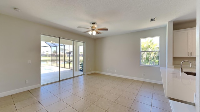 spare room with baseboards, light tile patterned floors, ceiling fan, and a sink