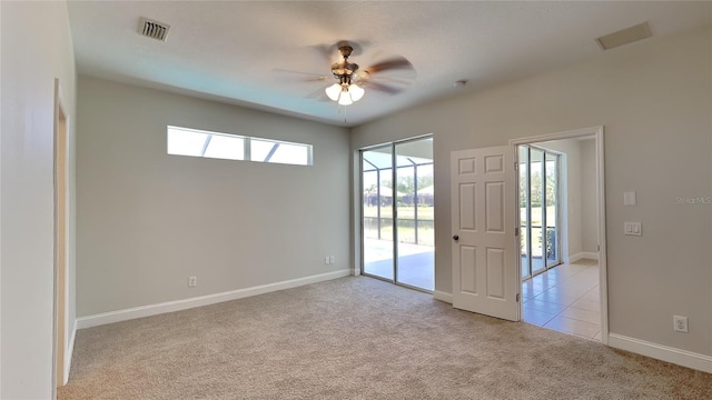 empty room with visible vents, carpet flooring, baseboards, and a ceiling fan