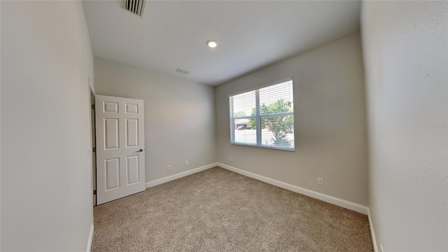carpeted spare room with visible vents and baseboards