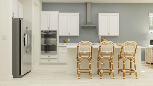 12054 Violet Jasper Dr, Parrish, FL 34219 - kitchen featuring appliances with stainless steel finishes, light countertops, white cabinets, a breakfast bar, and wall chimney exhaust hood