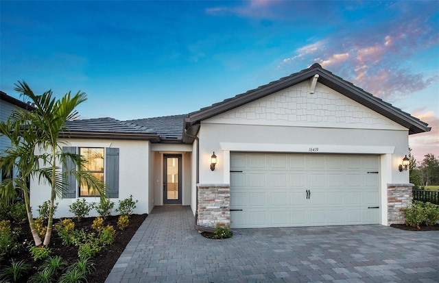 ranch-style house with a garage, stucco siding, driveway, and stone siding