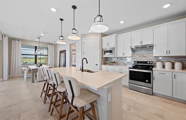 kitchen featuring a kitchen island with sink, a sink, appliances with stainless steel finishes, and backsplash