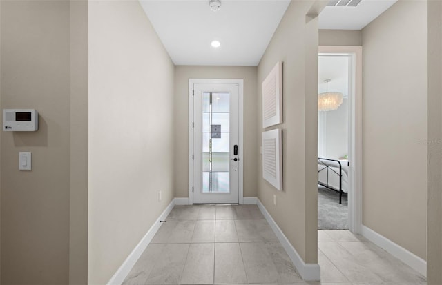 doorway featuring baseboards, light tile patterned flooring, and visible vents