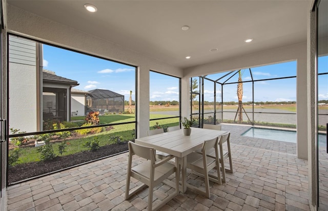 sunroom featuring outdoor dining area and a water view