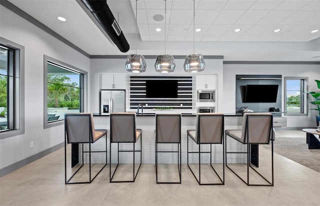 kitchen featuring stainless steel appliances, open floor plan, white cabinetry, and decorative light fixtures
