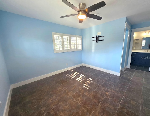 unfurnished room featuring baseboards, ceiling fan, and a sink
