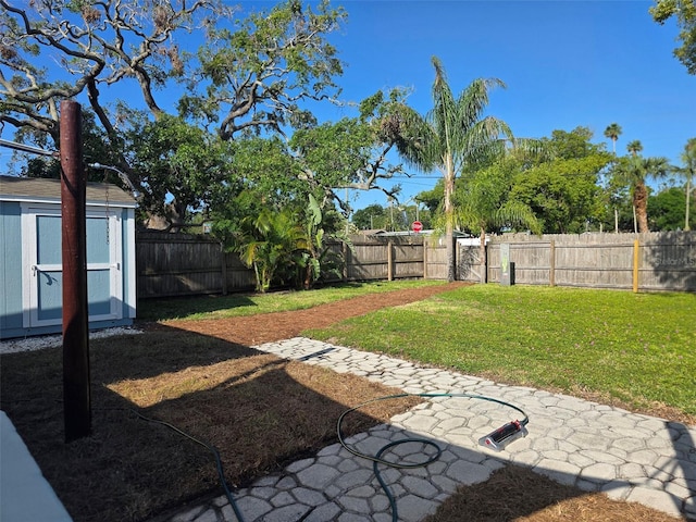view of yard with a storage unit, an outdoor structure, a fenced backyard, and a patio area