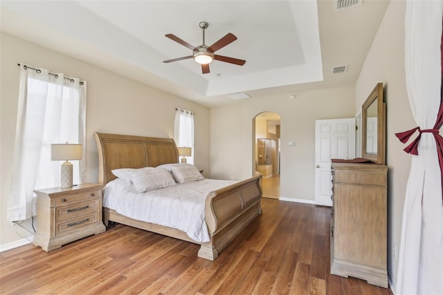 20254 Ravens End Dr, Tampa, FL 33647 - bedroom with a raised ceiling, arched walkways, baseboards, wood finished floors, and visible vents