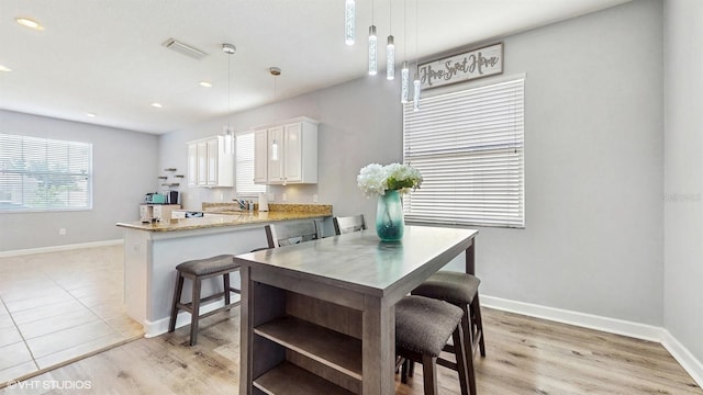 interior space with baseboards, a peninsula, white cabinetry, and decorative light fixtures