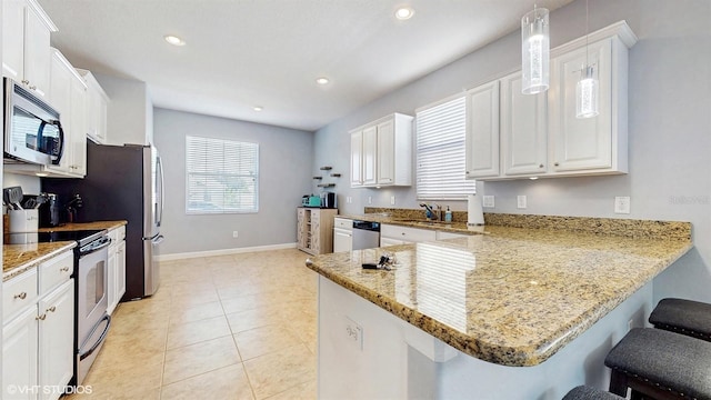 kitchen featuring appliances with stainless steel finishes, a breakfast bar area, a peninsula, and white cabinetry
