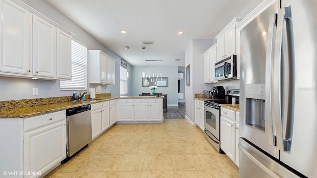 kitchen featuring appliances with stainless steel finishes, a sink, a peninsula, white cabinetry, and stone counters