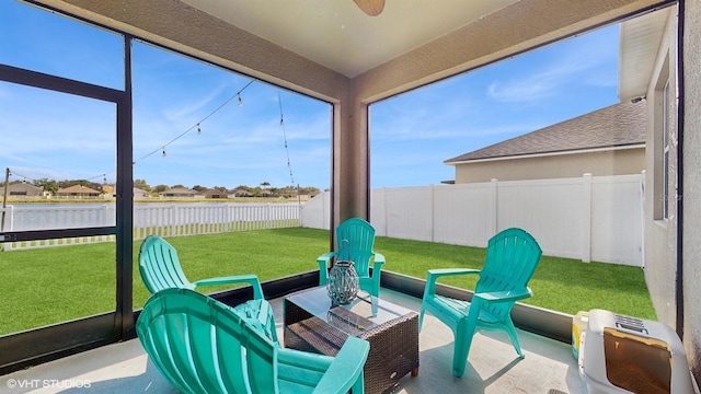 sunroom featuring a ceiling fan and a water view