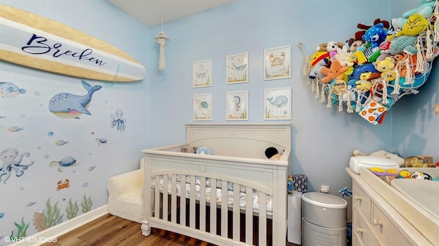 bedroom featuring a crib and wood finished floors