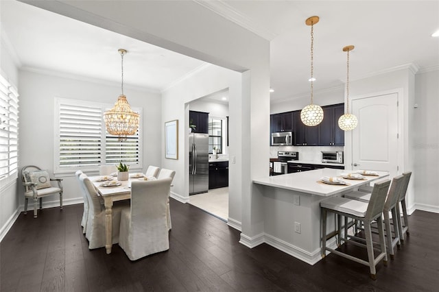 kitchen featuring appliances with stainless steel finishes, light countertops, dark wood-style floors, a notable chandelier, and a breakfast bar