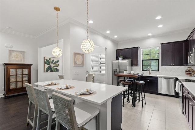 kitchen with light countertops, stainless steel appliances, crown molding, and decorative backsplash
