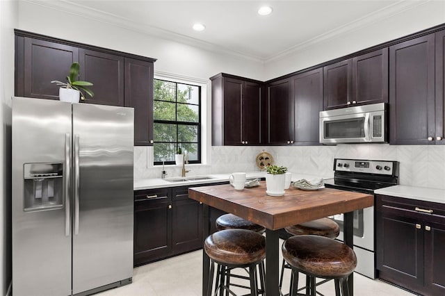 kitchen with crown molding, appliances with stainless steel finishes, a sink, light countertops, and backsplash