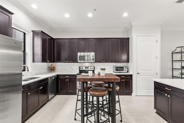 kitchen with backsplash, crown molding, appliances with stainless steel finishes, a sink, and light countertops