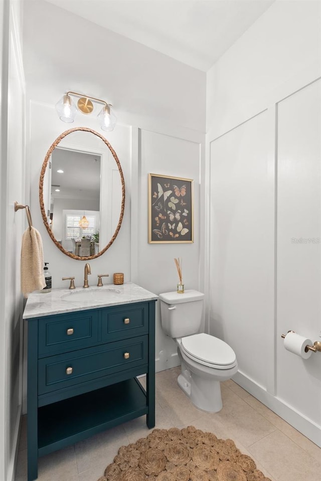 half bathroom with toilet, tile patterned flooring, and vanity