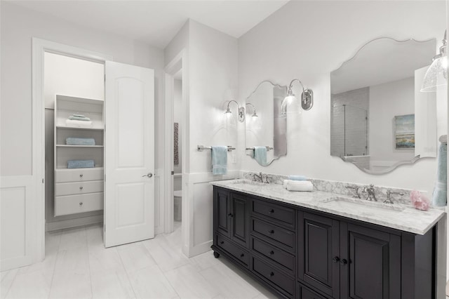 full bath featuring double vanity, a sink, marble finish floor, and a stall shower