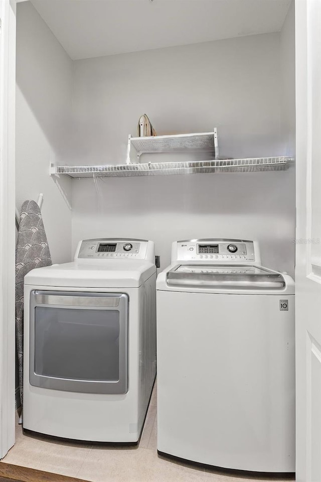 laundry area featuring light tile patterned floors, laundry area, and washer and clothes dryer