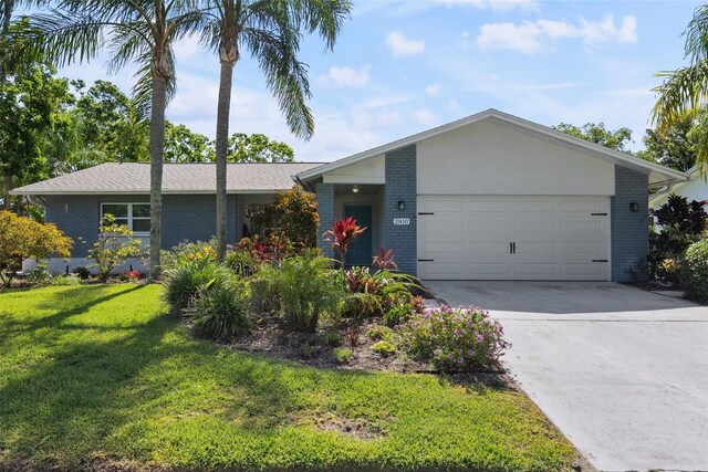 single story home with brick siding, a garage, a front yard, and concrete driveway