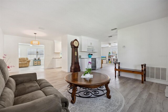 living area with visible vents, light wood-style floors, ceiling fan, and beverage cooler