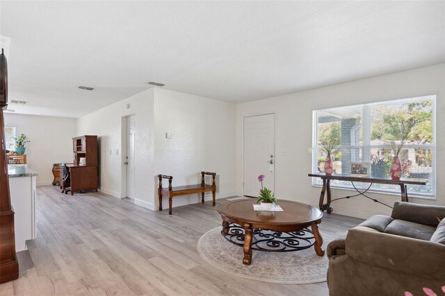 living area with baseboards, visible vents, and light wood-type flooring