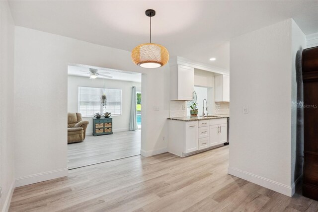 kitchen with baseboards, ceiling fan, light wood-type flooring, white cabinetry, and tasteful backsplash