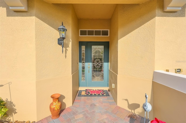 view of exterior entry with visible vents and stucco siding