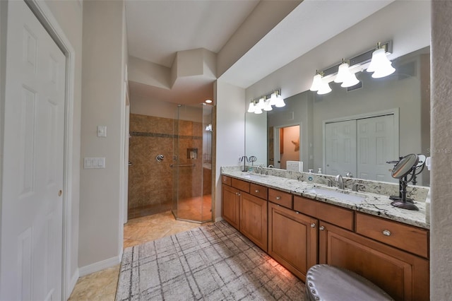 full bath with a sink, tile patterned flooring, double vanity, and tiled shower