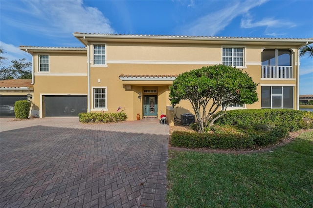 mediterranean / spanish-style house featuring decorative driveway, central AC unit, a garage, and stucco siding