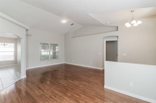 2203 Malaga Ave, Spring Hill, FL 34609 - spare room with a chandelier, arched walkways, wood finished floors, vaulted ceiling, and baseboards