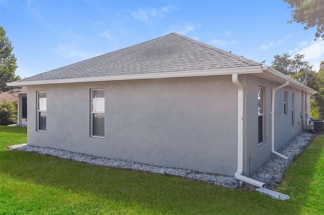 2203 Malaga Ave, Spring Hill, FL 34609 - view of property exterior with stucco siding, a yard, roof with shingles, and central air condition unit