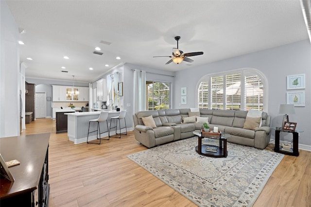living area featuring ceiling fan, light wood finished floors, arched walkways, recessed lighting, and baseboards