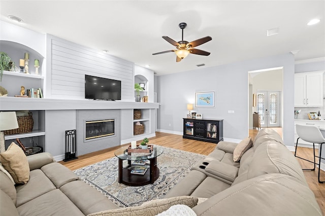 living area featuring visible vents, a ceiling fan, light wood-style flooring, and a fireplace