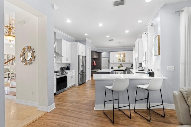 kitchen with appliances with stainless steel finishes, a sink, a peninsula, visible vents, and ornamental molding