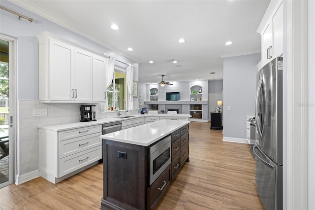 kitchen with crown molding, open floor plan, light countertops, white cabinetry, and appliances with stainless steel finishes