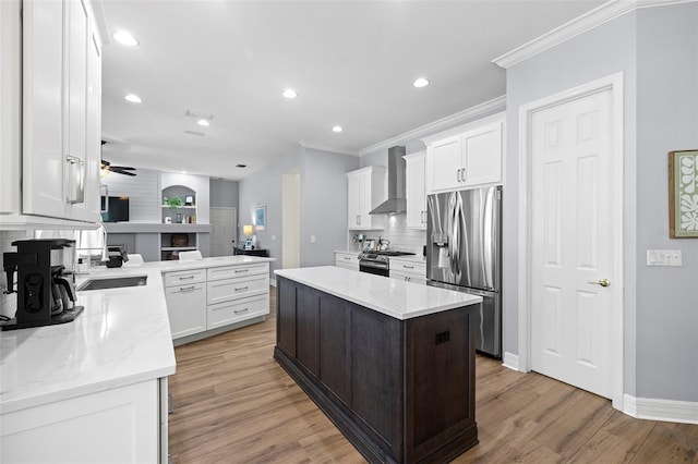 kitchen with crown molding, wall chimney exhaust hood, stainless steel appliances, decorative backsplash, and a kitchen island