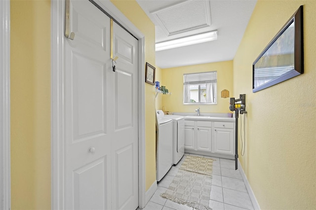laundry room featuring baseboards, washing machine and clothes dryer, a sink, cabinet space, and light tile patterned floors
