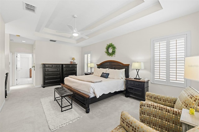bedroom featuring baseboards, light carpet, a tray ceiling, and visible vents