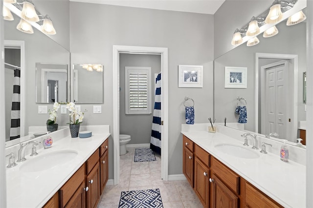 bathroom featuring a sink, toilet, and two vanities