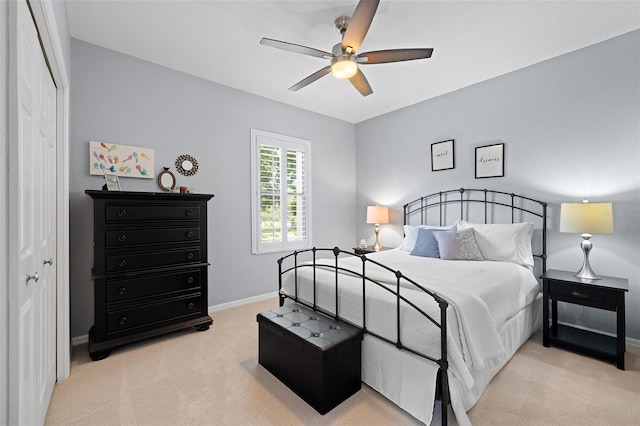 bedroom with a ceiling fan, baseboards, light carpet, and a closet