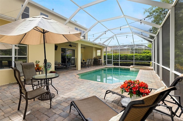 view of swimming pool featuring a patio, outdoor dining area, ceiling fan, and glass enclosure