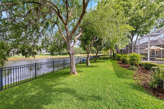 view of yard with a water view, fence, and a lanai