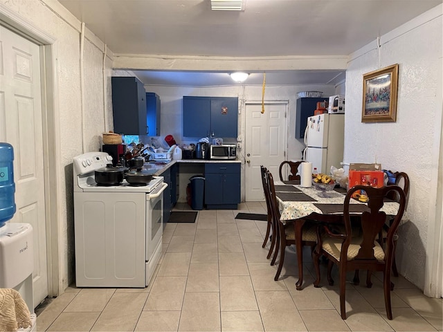 kitchen with washer / clothes dryer, light tile patterned floors, white appliances, blue cabinets, and a textured wall