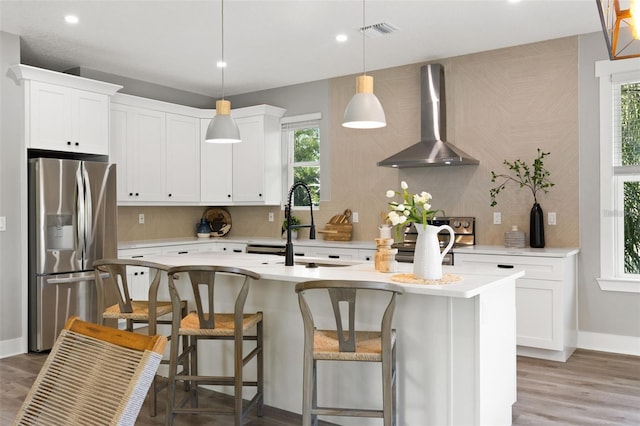 116 W Stanley St, Tampa, FL 33604 - kitchen featuring stainless steel appliances, wall chimney range hood, light countertops, backsplash, and a center island with sink