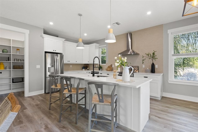 116 W Stanley St, Tampa, FL 33604 - kitchen featuring wall chimney range hood, appliances with stainless steel finishes, a sink, light countertops, and light wood finished floors
