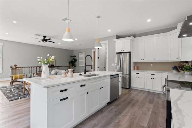 116 W Stanley St, Tampa, FL 33604 - kitchen featuring appliances with stainless steel finishes, a sink, light wood-style flooring, a kitchen island with sink, and recessed lighting