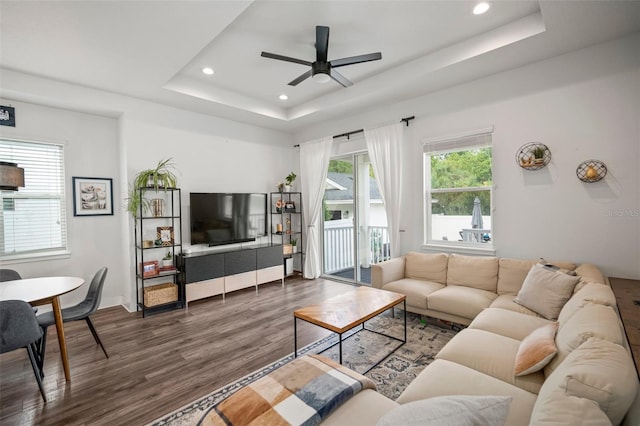 living area featuring recessed lighting, ceiling fan, wood finished floors, and a tray ceiling