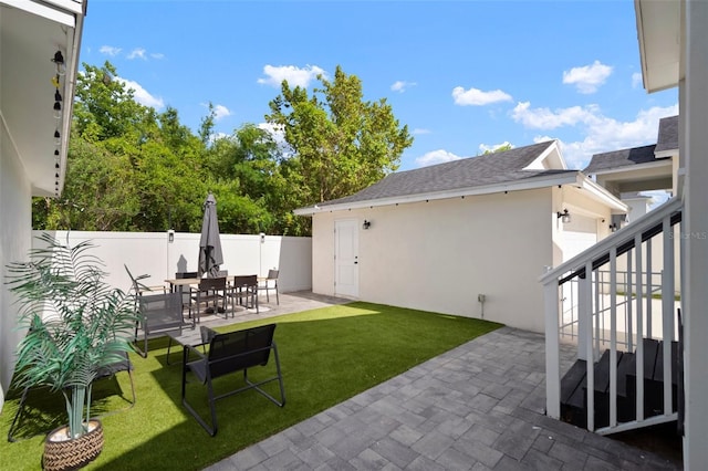 view of yard featuring a patio, fence, stairs, and outdoor dining space
